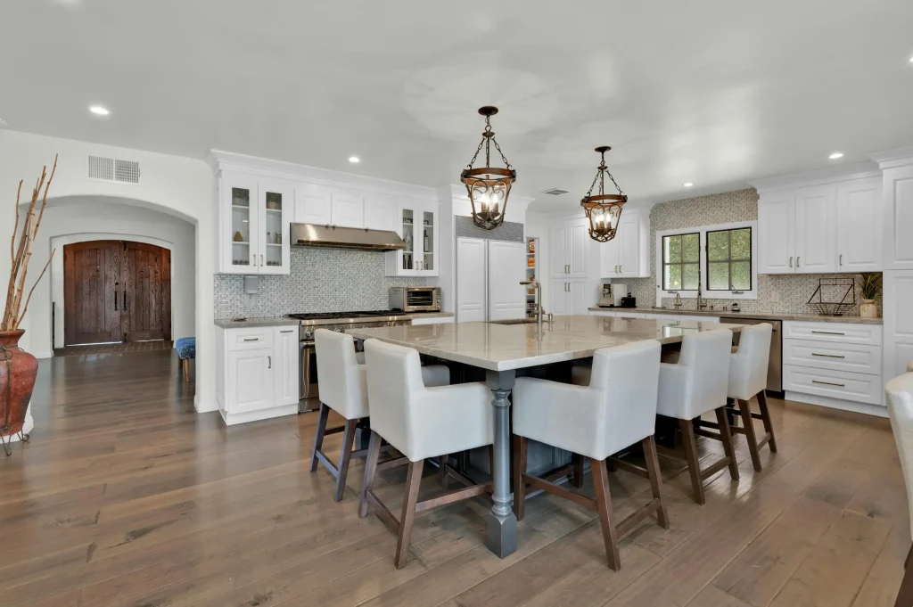 Bathroom and kitchen remodeling Concord CA with white cabinets, large island dining table, lantern pendants, open floor plan